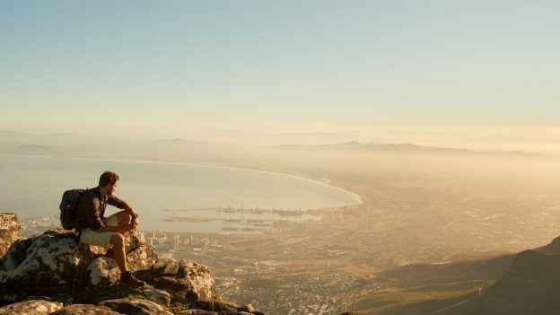 Shot of a young hiker admiring the view from the top of the mountain